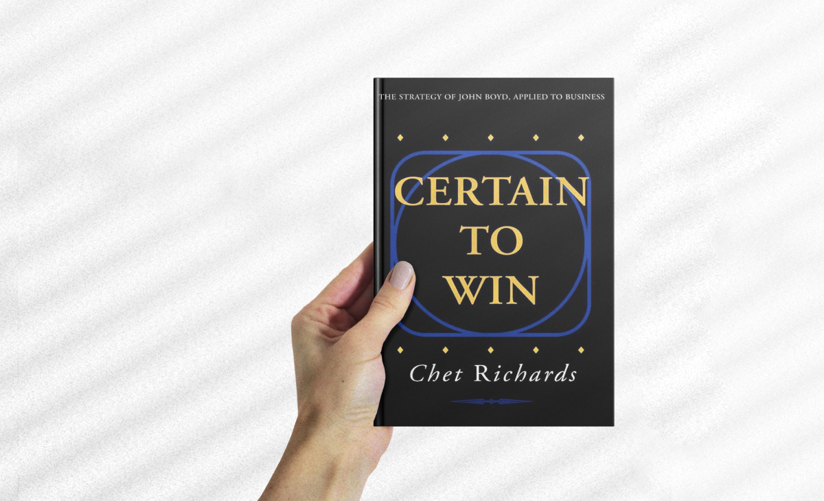 Digital image of a left hand holding the book "Certain to Win," which frankly, doesn't have a very exciting cover. But it's a great book.